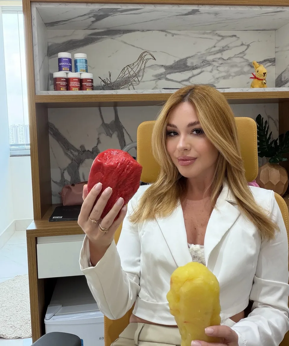 Mirella Sordi gravando conteúdo no consultório, segurando um pimentão vermelho e um amarelo